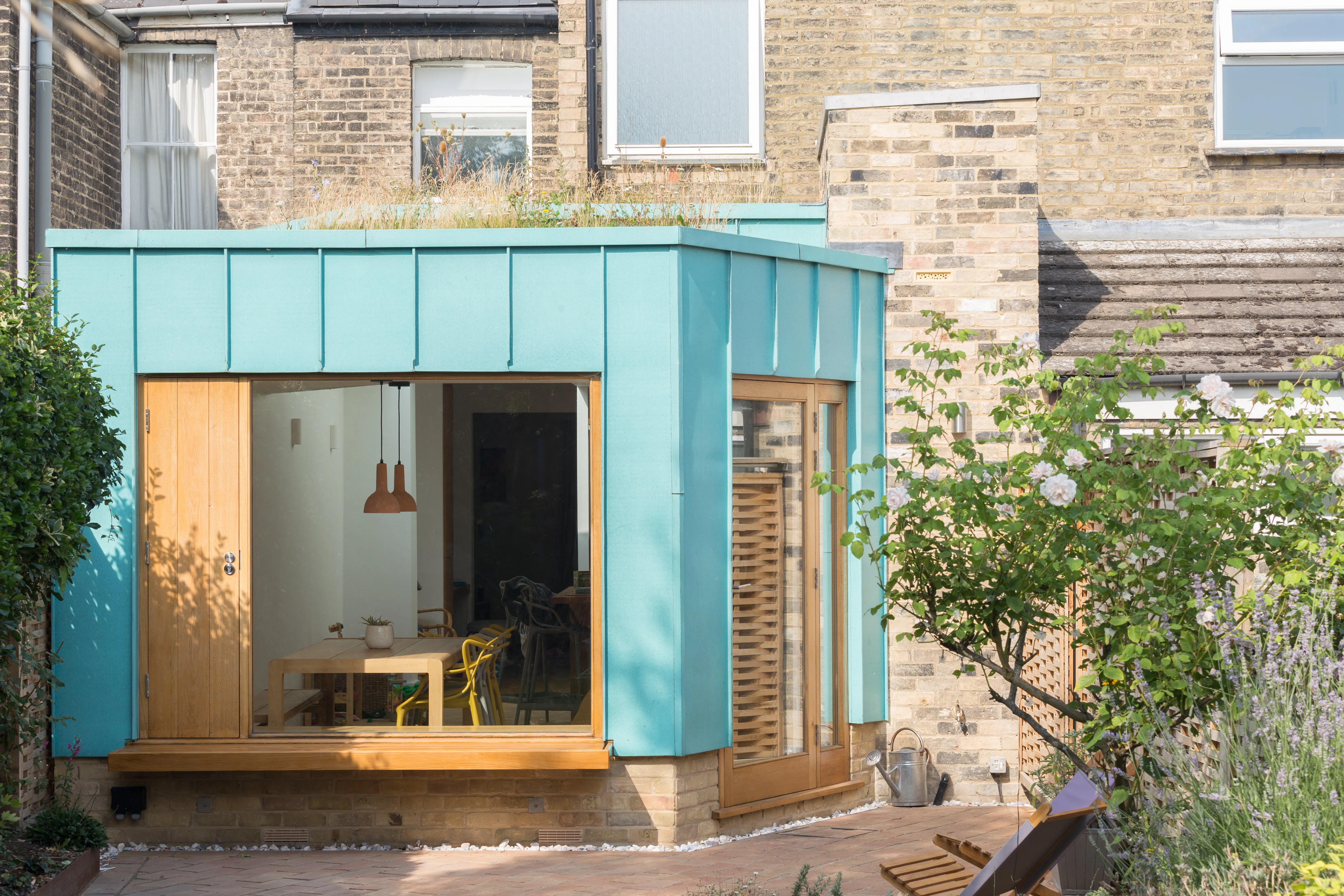 Copper House, a patinated-copper extension set within a conservation area, opening onto a landscaped setting